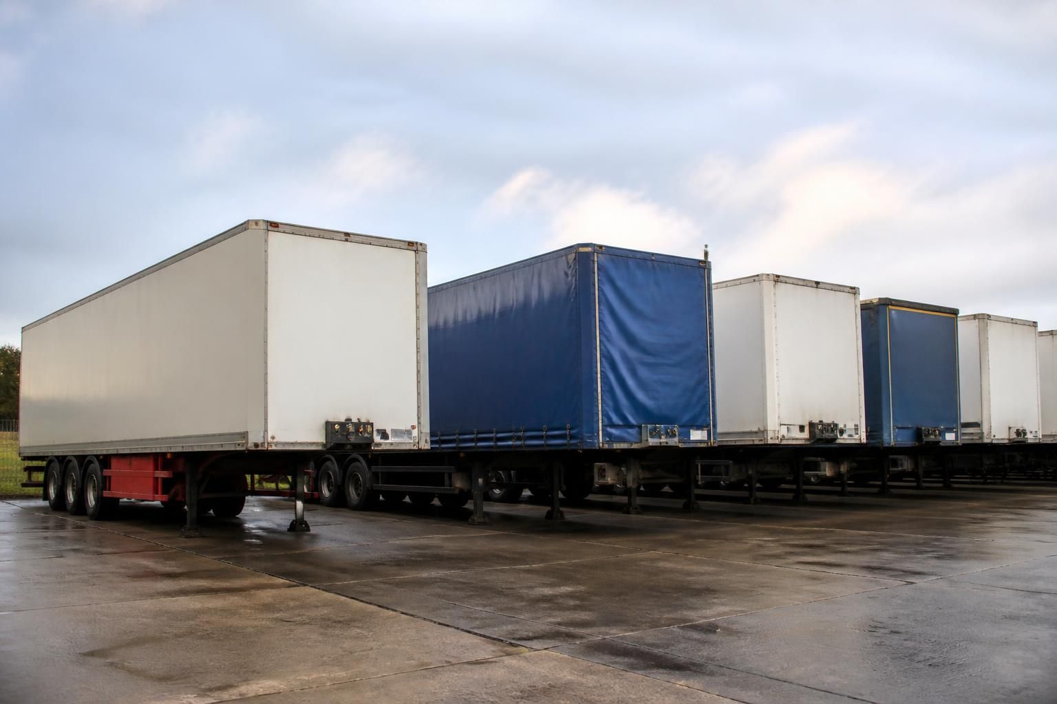 Uncoupled curtainside and box trailers parked in a haulage yard