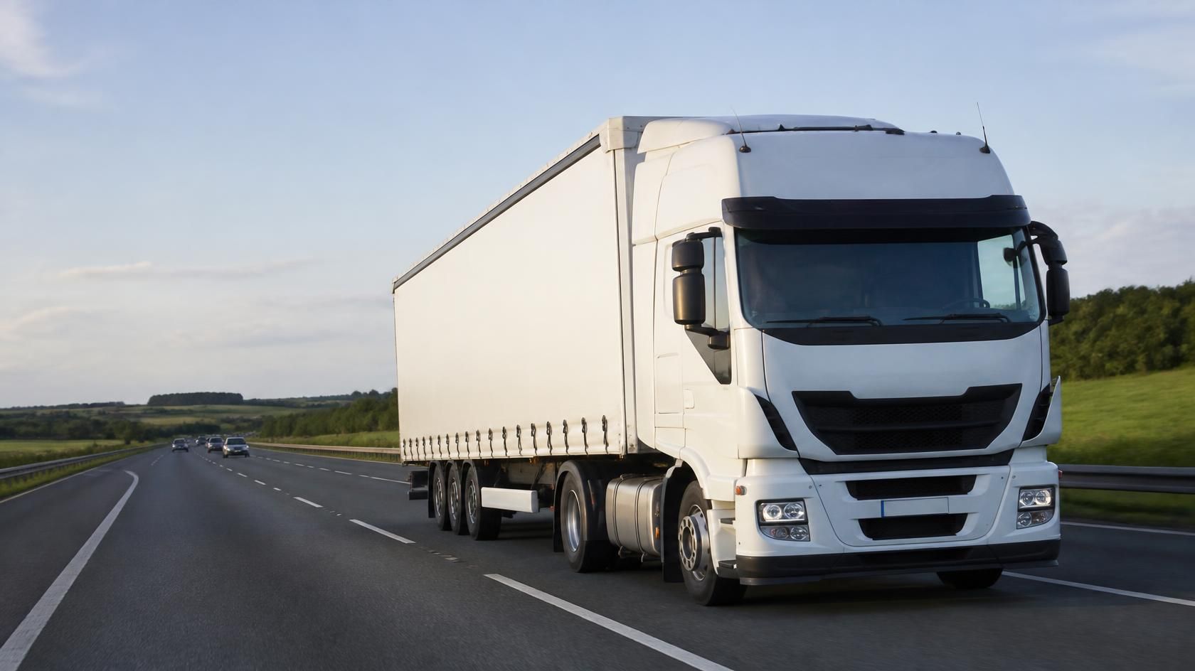 White articulated lorry travelling along a motorway through green countryside