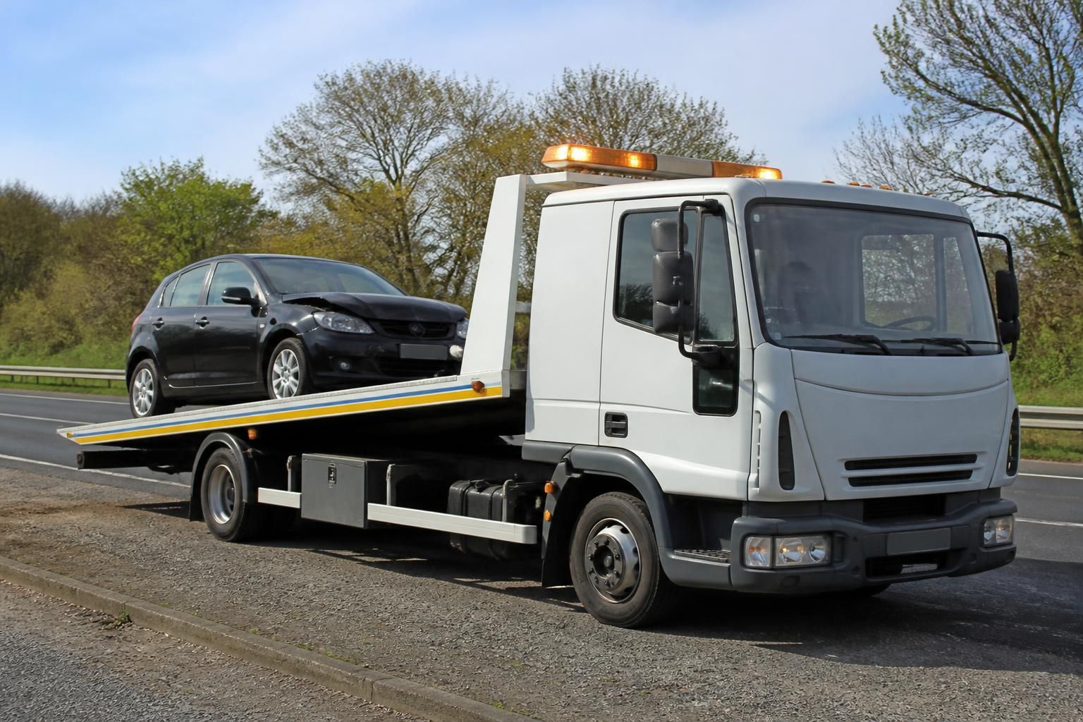 Slide bed recovery truck carrying a car