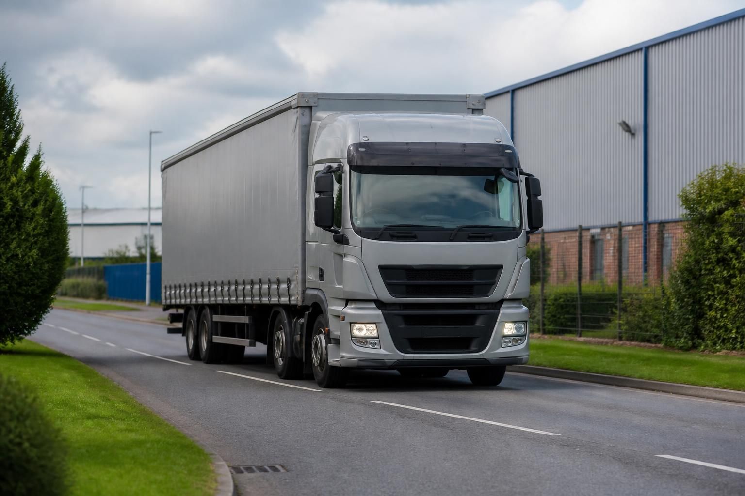 Rigid curtainside lorry driving through an industrial estate